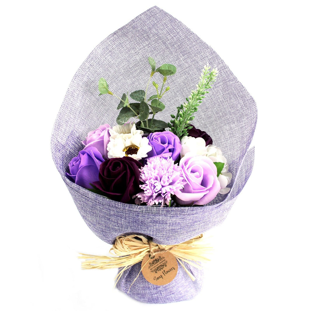 A standing bouquet of realistic purple and lavender soap flowers wrapped in decorative paper with a purple ribbon.