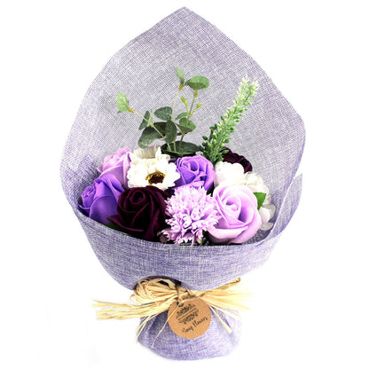 A standing bouquet of realistic purple and lavender soap flowers wrapped in decorative paper with a purple ribbon.