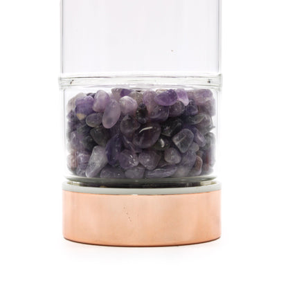 A sleek glass water bottle with rose gold metallic accents and a base compartment filled with polished purple Amethyst gemstones.