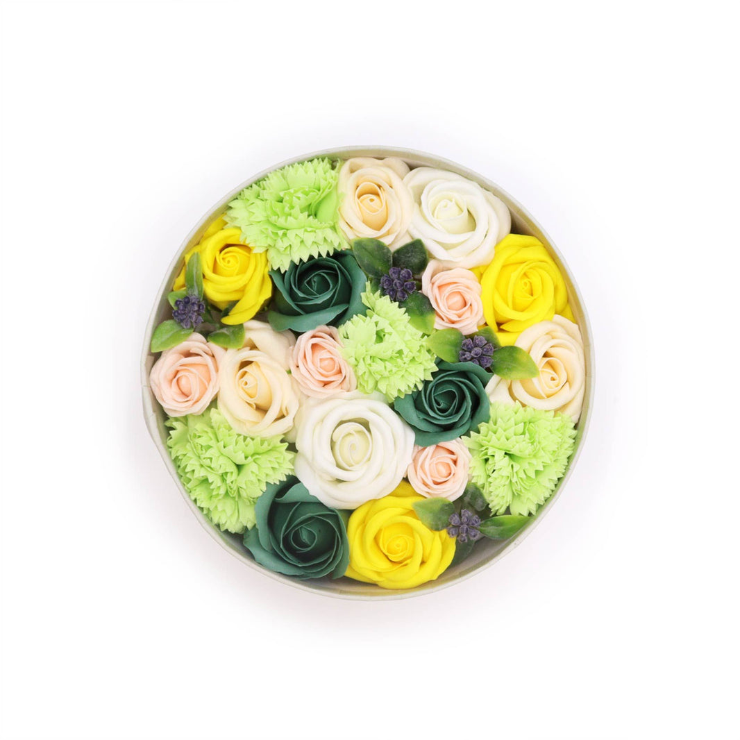 A decorative round gift box filled with realistic yellow and green soap flowers designed to look like a fresh Spring bouquet.