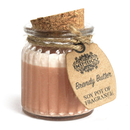 A small glass candle pot with tan-colored soy wax, a cork lid, and a rustic paper label tied with string.
