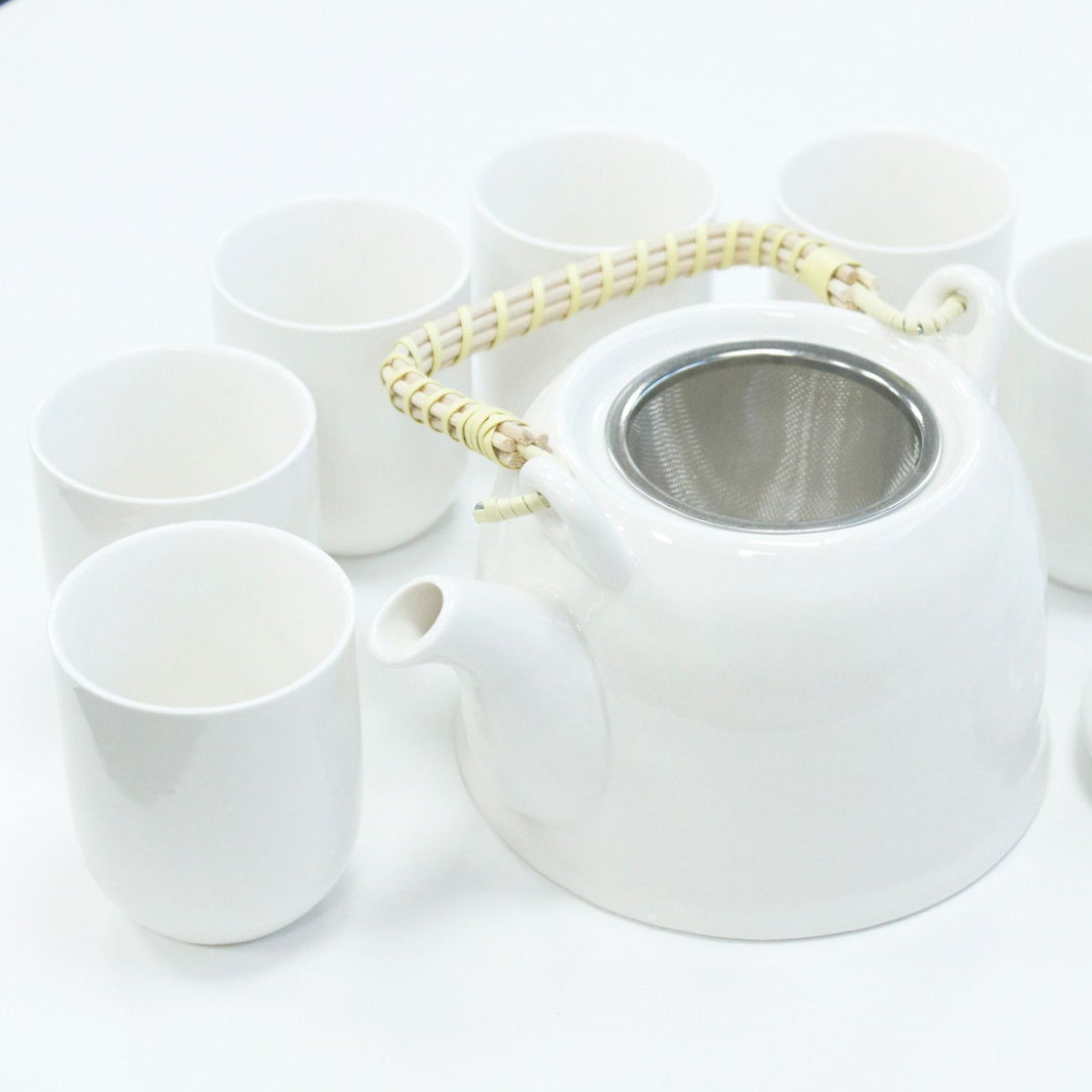 A clean, bright white ceramic teapot set including a teapot with a bamboo handle and matching white handleless cups.