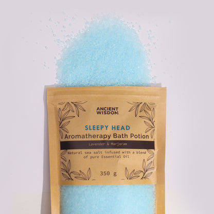 A rustic paper bag filled with light blue and lavender aromatherapy bath salts with a calming essential oil scent.