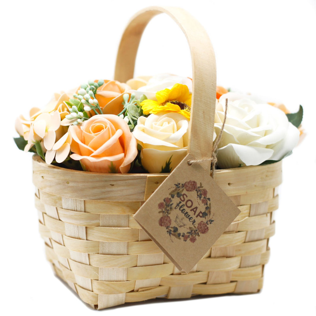 A large decorative wicker basket filled with realistic orange and yellow soap roses and lush greenery.