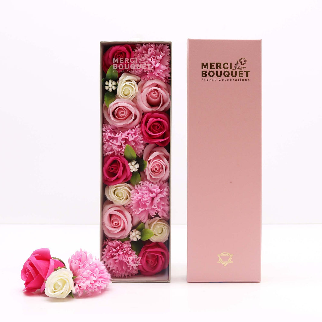 An elegant pink long gift box containing realistic pink soap roses and white flowers, designed as a new baby or baby shower gift.