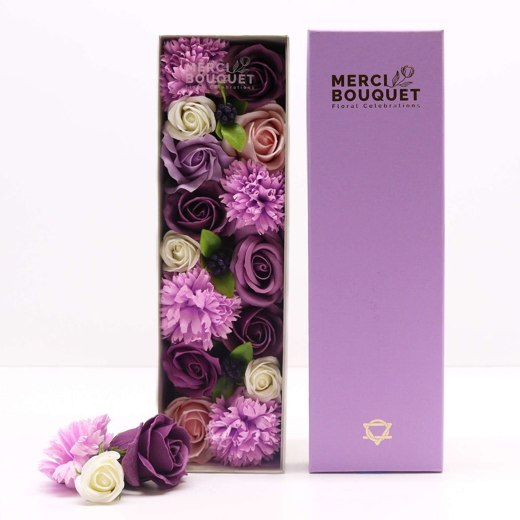 A purple long gift box displaying a beautiful arrangement of realistic lavender soap roses and carnations.
