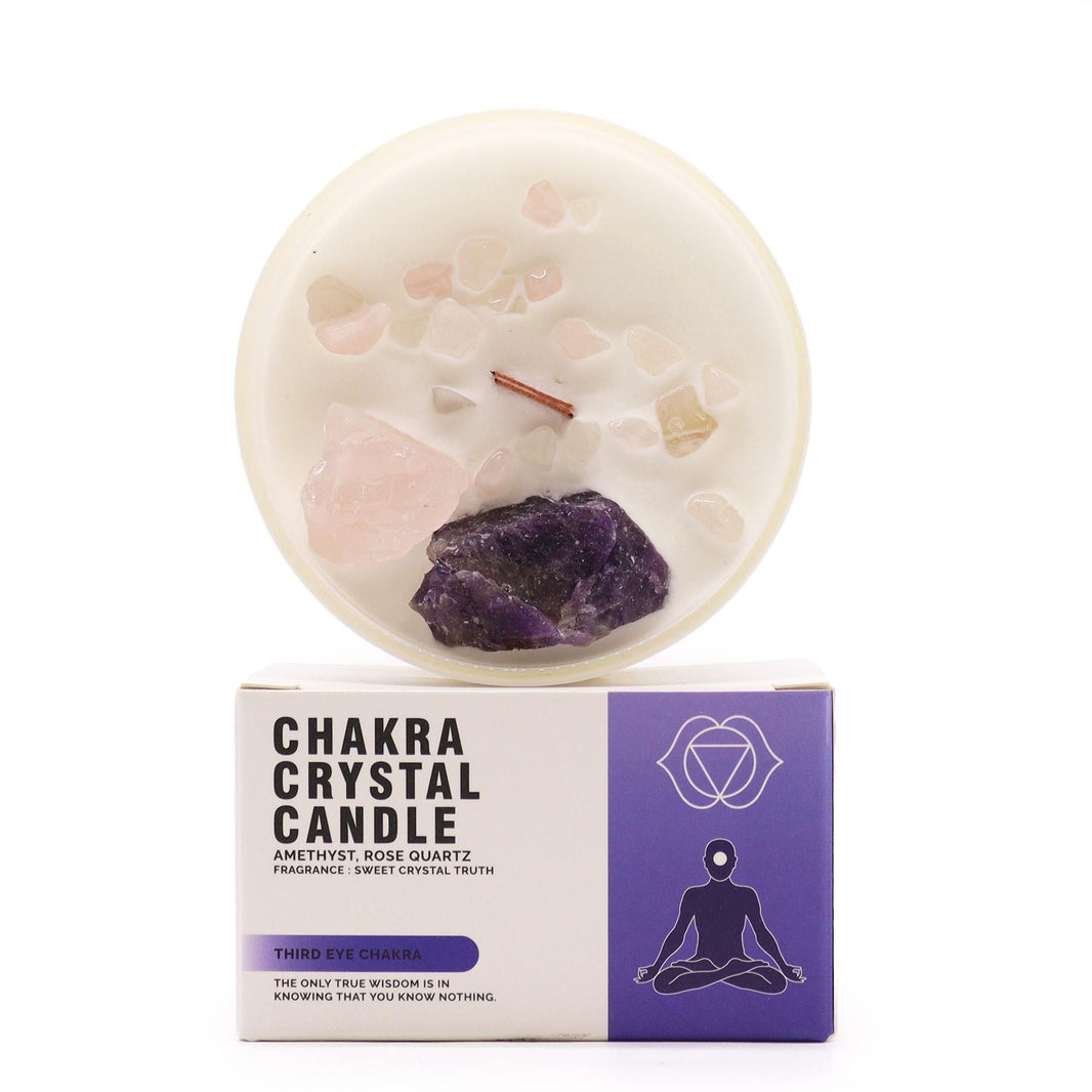 A Third Eye Chakra candle in a jar topped with raw purple Amethyst gemstones and dried botanicals, with its branded box.
