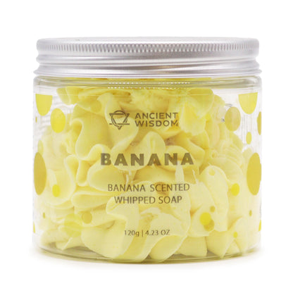 A clear glass jar overflowing with vibrant yellow whipped cream soap featuring a thick, decadent, and pipeable texture.