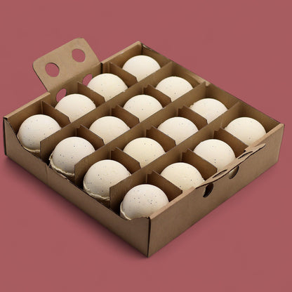 A cardboard display box holding 16 individually wrapped 180g vanilla bath bombs in cream tones.