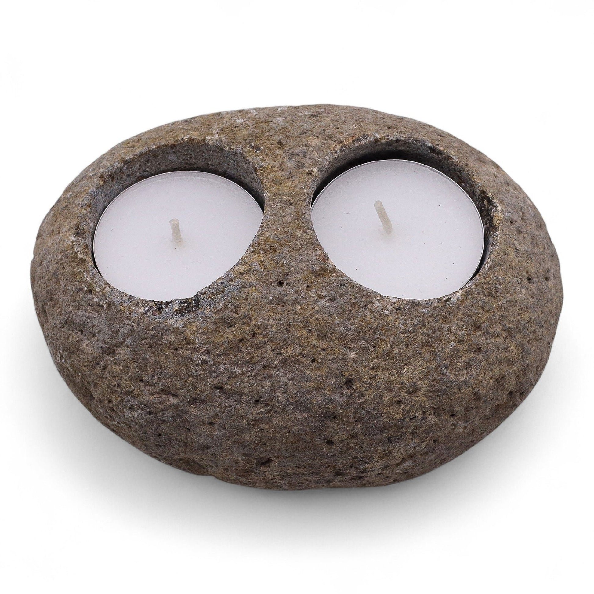 Two smooth grey riverstones stacked or arranged together, each holding a tea light for a serene spa atmosphere.