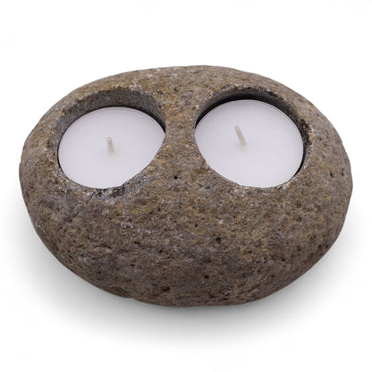 Two smooth grey riverstones stacked or arranged together, each holding a tea light for a serene spa atmosphere.