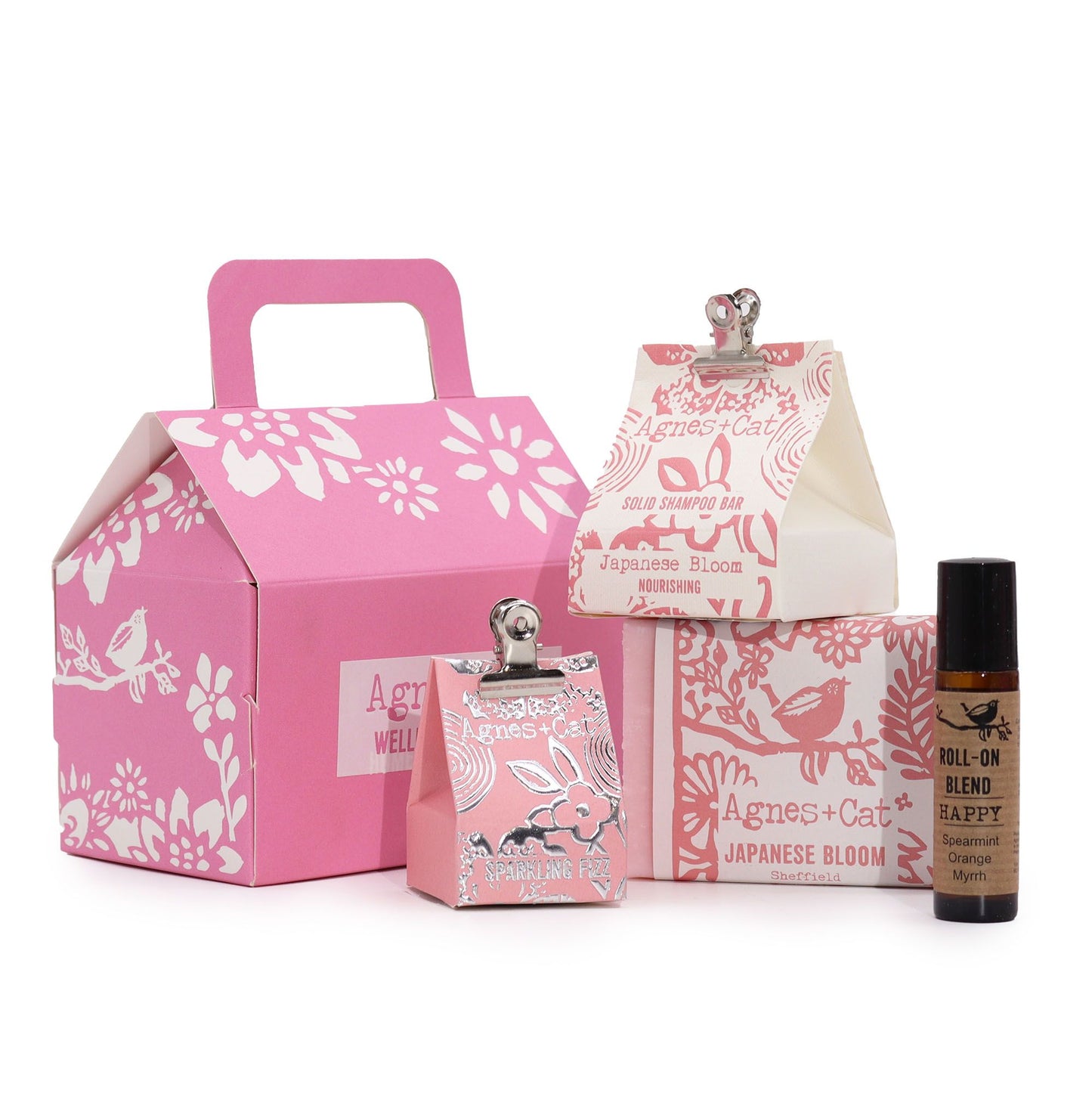 A premium pink gift box featuring a variety of floral-themed bath treats, salts, and a candle in a curated display.