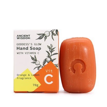 A bright orange, oval-shaped hand soap bar resting next to its white and orange illustrated packaging.