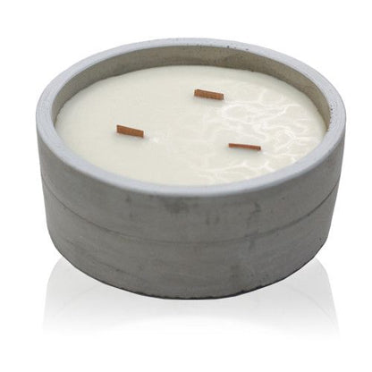 A large, round grey concrete candle pot filled with white soy wax and featuring three wicks for an even burn.