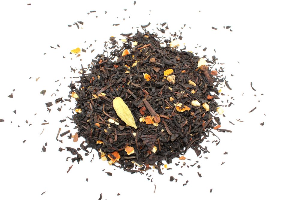 A dense pile of dark, high-quality loose-leaf black tea leaves with subtle inclusions of spices and botanical elements.