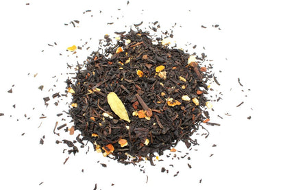 A dense pile of dark, high-quality loose-leaf black tea leaves with subtle inclusions of spices and botanical elements.