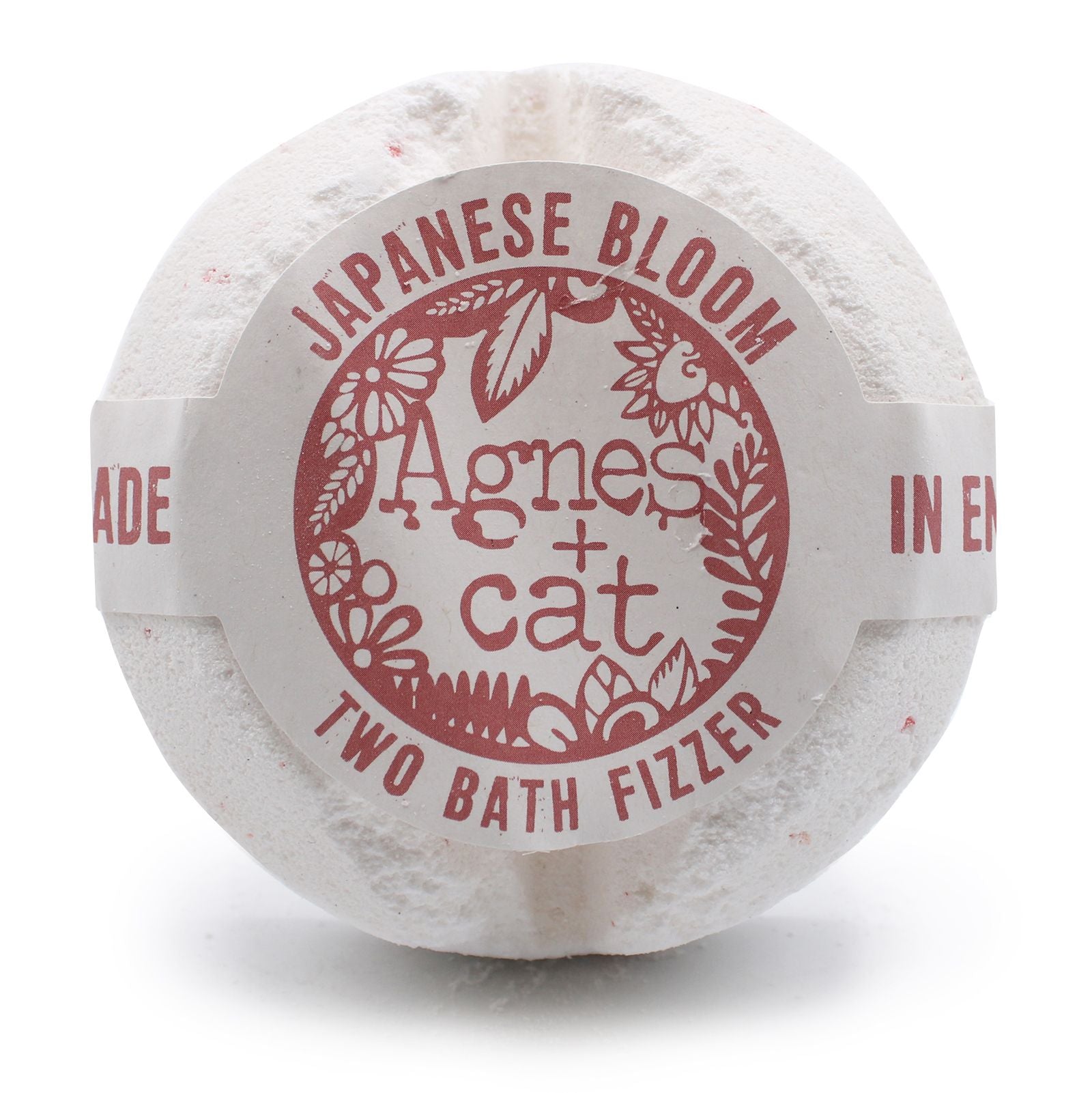A large spherical bath fizzer with a soft red and white label featuring Japanese floral motifs.