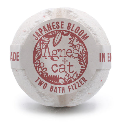 A large spherical bath fizzer with a soft red and white label featuring Japanese floral motifs.