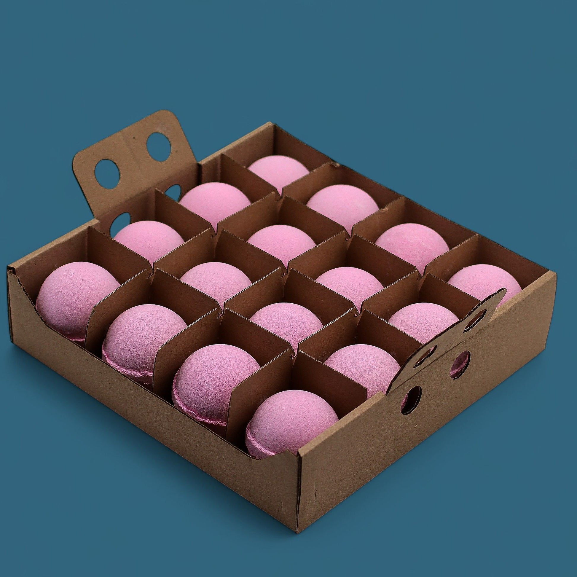 A cardboard display box holding 16 individually wrapped 180g Very Berry bath bombs in shades of pink and purple.