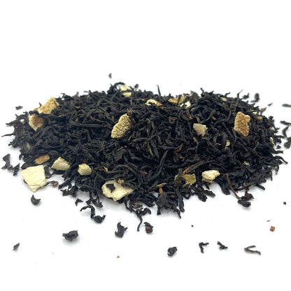 Bulk black loose-leaf tea leaves mixed with bright, dehydrated orange peel pieces and colorful flower petals.