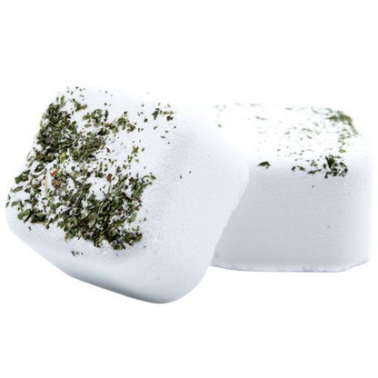 A white square shower steamer tablet infused with dried green herbs and invigorating citrus essential oils.