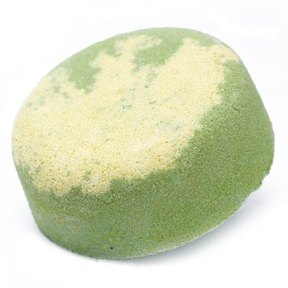 A round, pale green botanical bath bomb topped with real dried citrus peel and white flower petals.