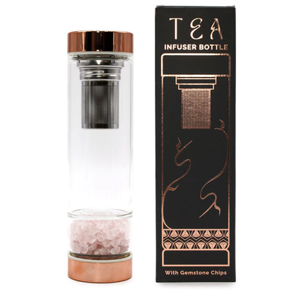 A glass travel tea bottle with rose gold metal caps and a separate compartment containing raw pink rose quartz gemstones.