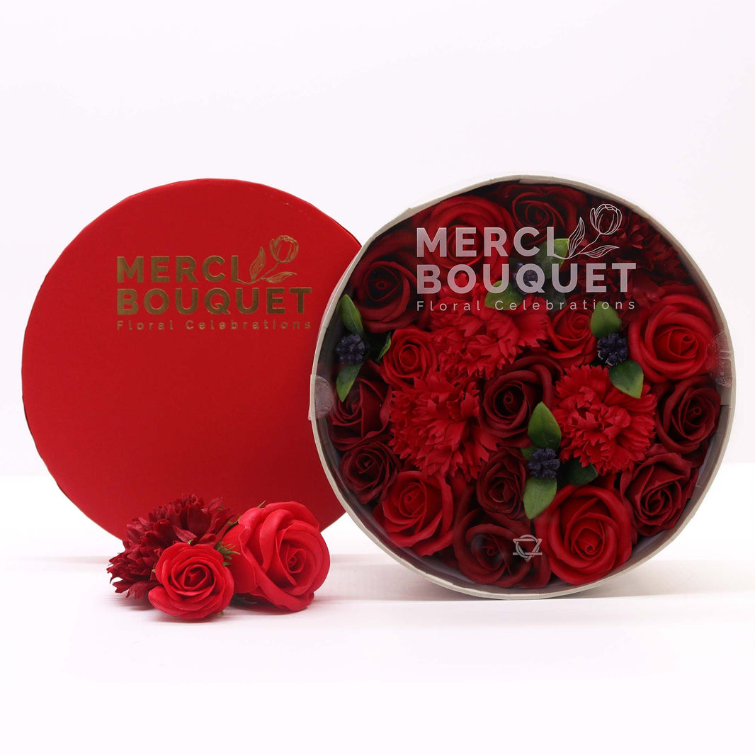 A premium round gift box packed with realistic, deep red soap rose flowers in a classic arrangement.
