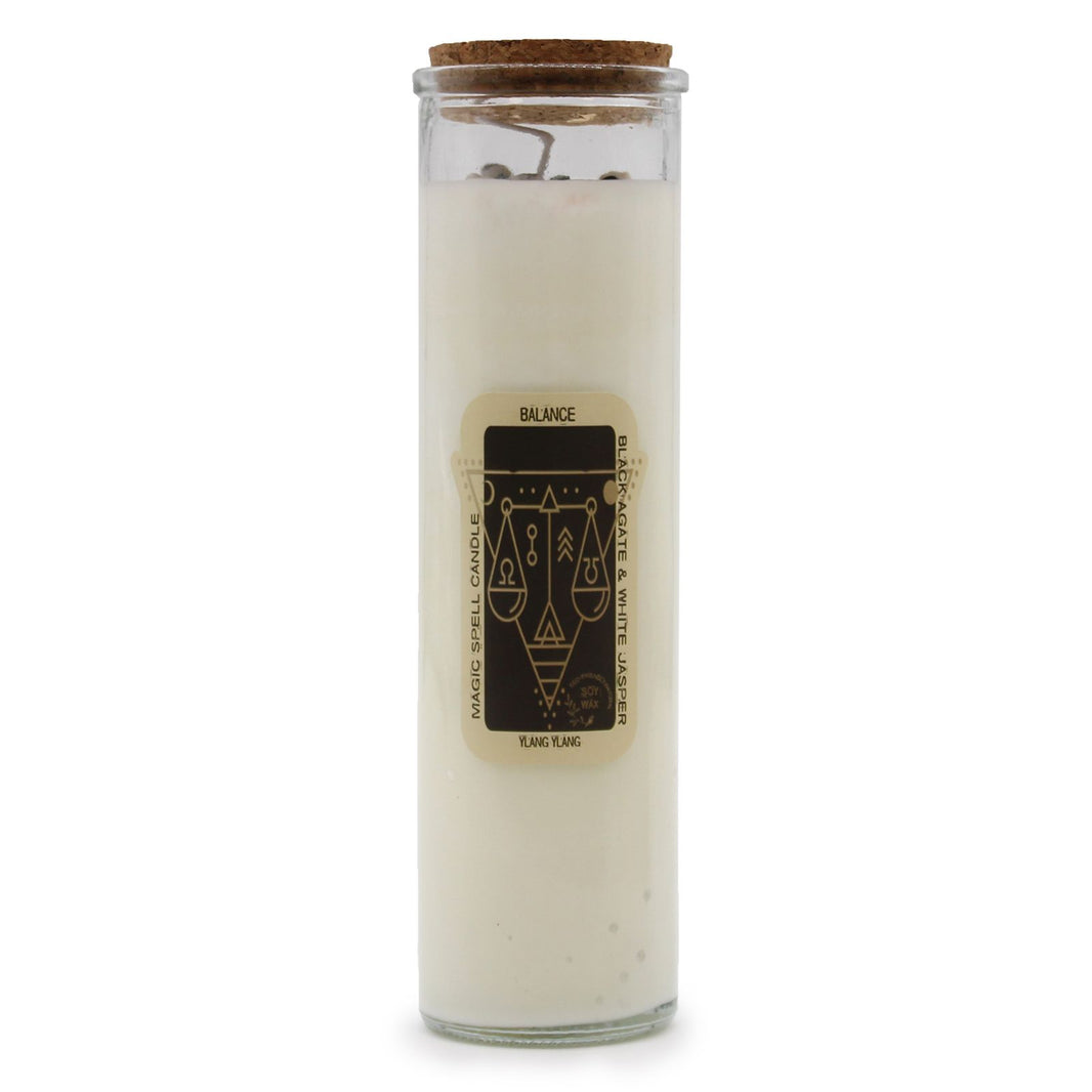 A tall, white magic spell candle wrapped in paper featuring mystical symbols and the word "Balance" in a decorative font.