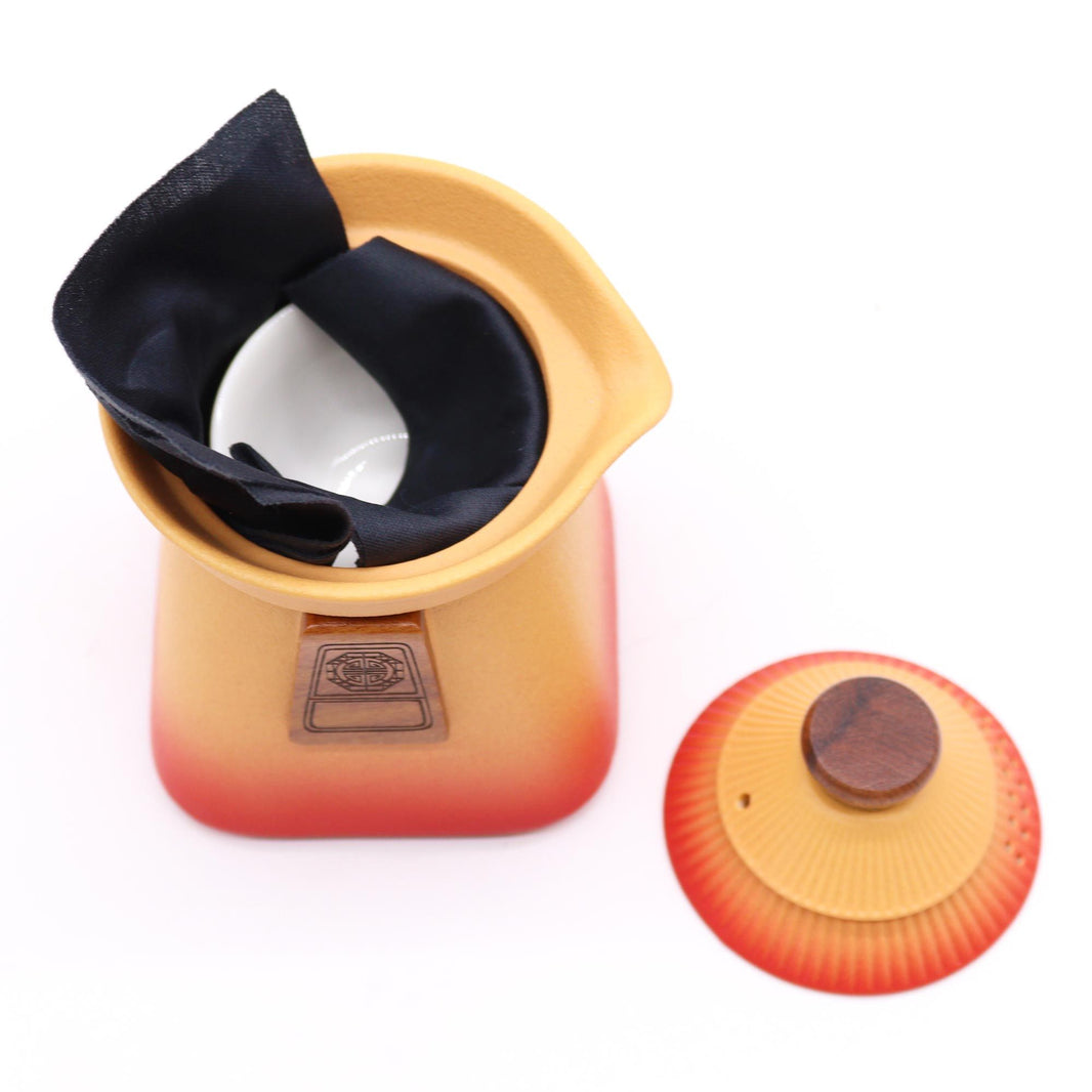 A modern ceramic teapot set in earthy orange tones, including a sleek, rounded teapot and three matching handleless cups.