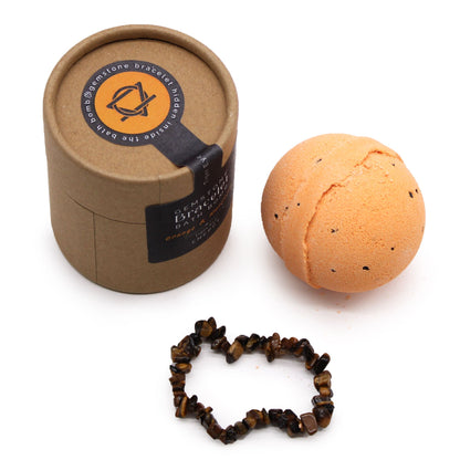 An orange-toned 170g bath bomb with a decorative Tiger Eye gemstone bracelet shown as the hidden surprise inside.