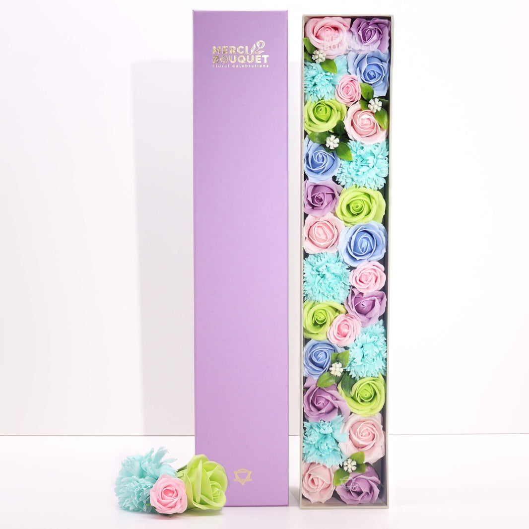 A tall, slim white gift box adorned with blue floral and baby-themed patterns, containing premium bath salts and soaps.