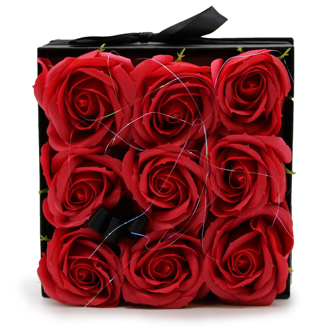A black square gift box featuring 9 realistic red soap roses arranged in a classic floral display.