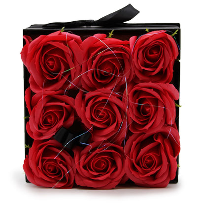 A black square gift box featuring 9 realistic red soap roses arranged in a classic floral display.