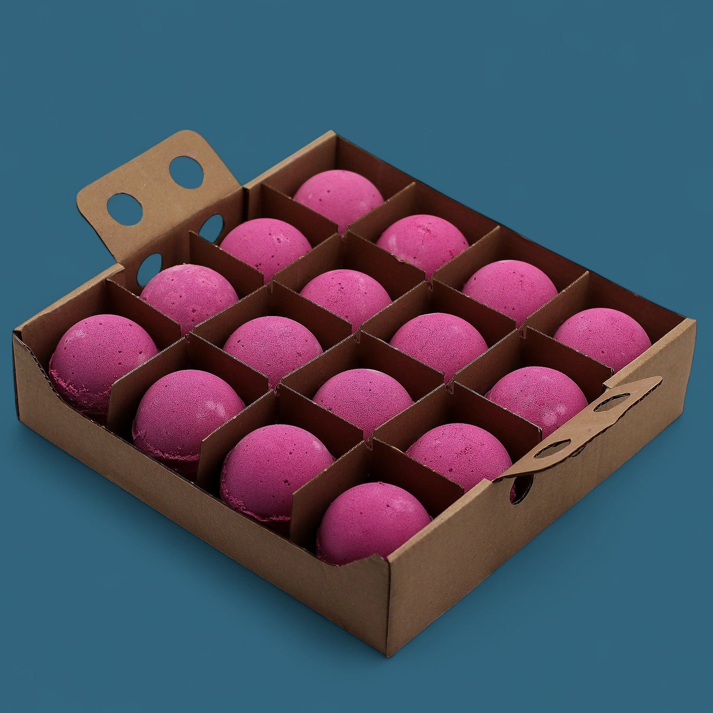 A wooden display tray holding a bulk grid of sixteen large, vibrant pinkish-red cranberry scented bath bombs.