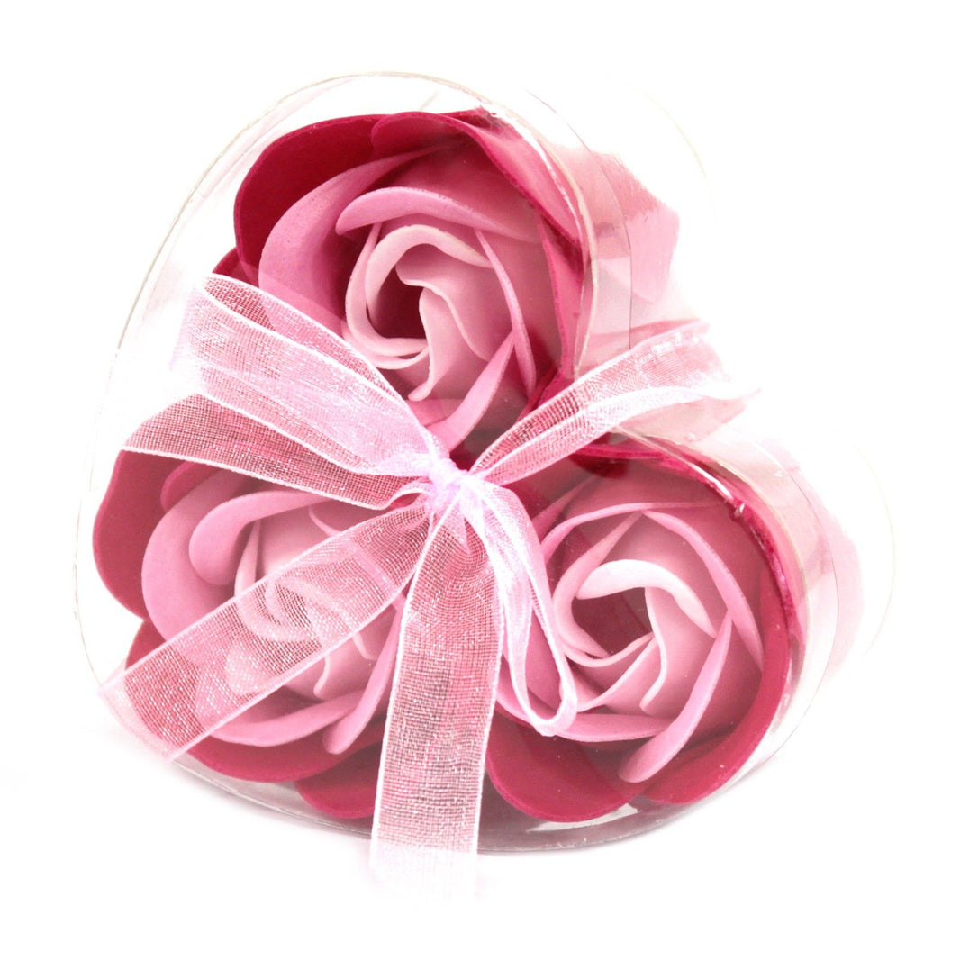 A small heart-shaped gift box containing three realistic pink soap rose flowers for a delicate bath ritual.