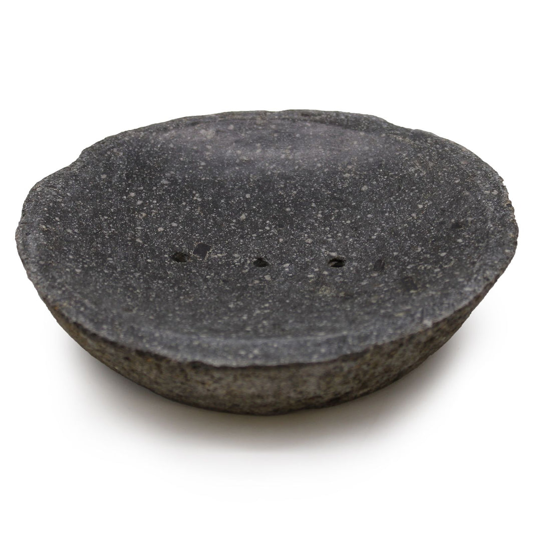 A dark, hand-carved natural riverstone soap dish with a smooth hollow and organic exterior shape.