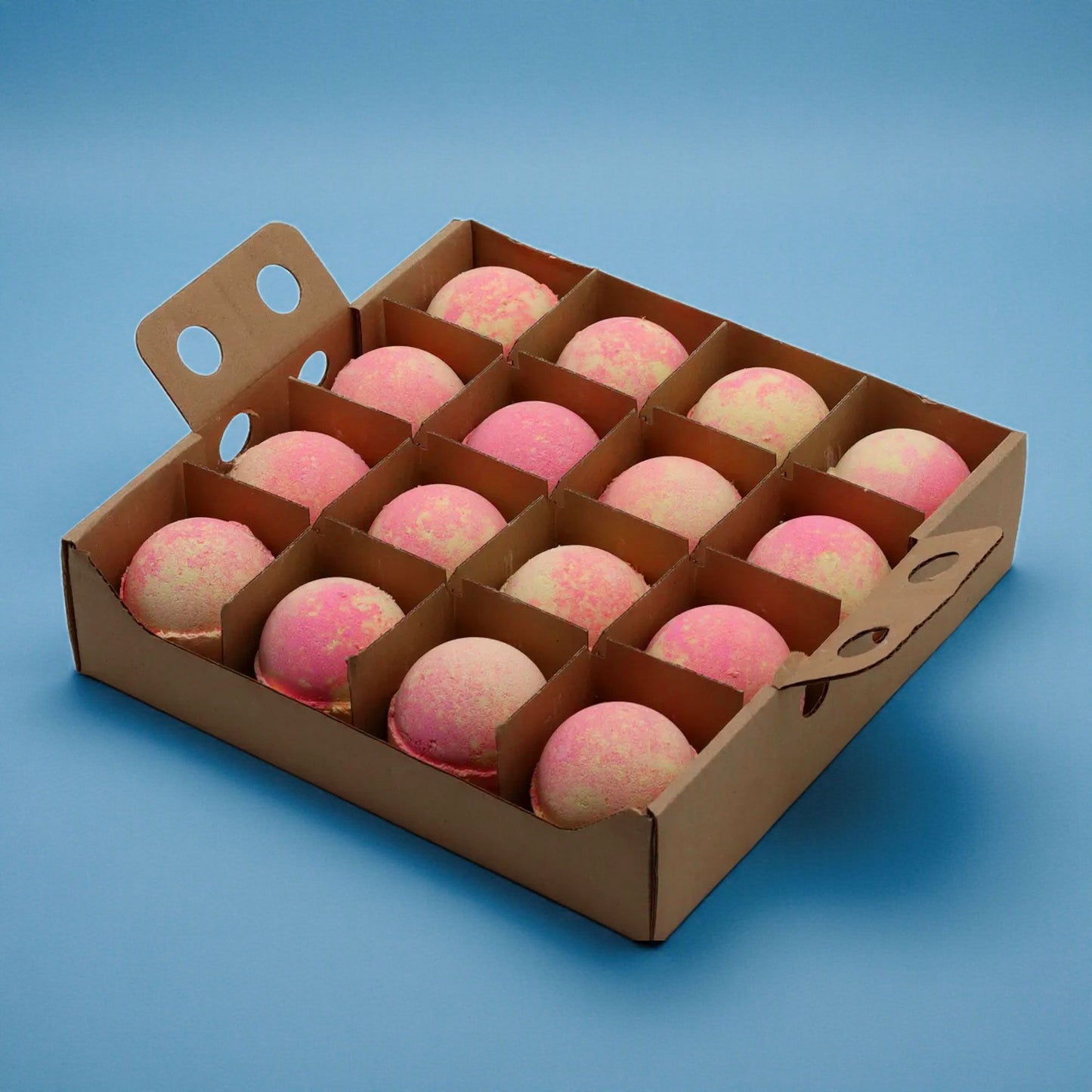 A bulk wooden display box containing sixteen round, pink-marbled bath bombs arranged in a neat grid.