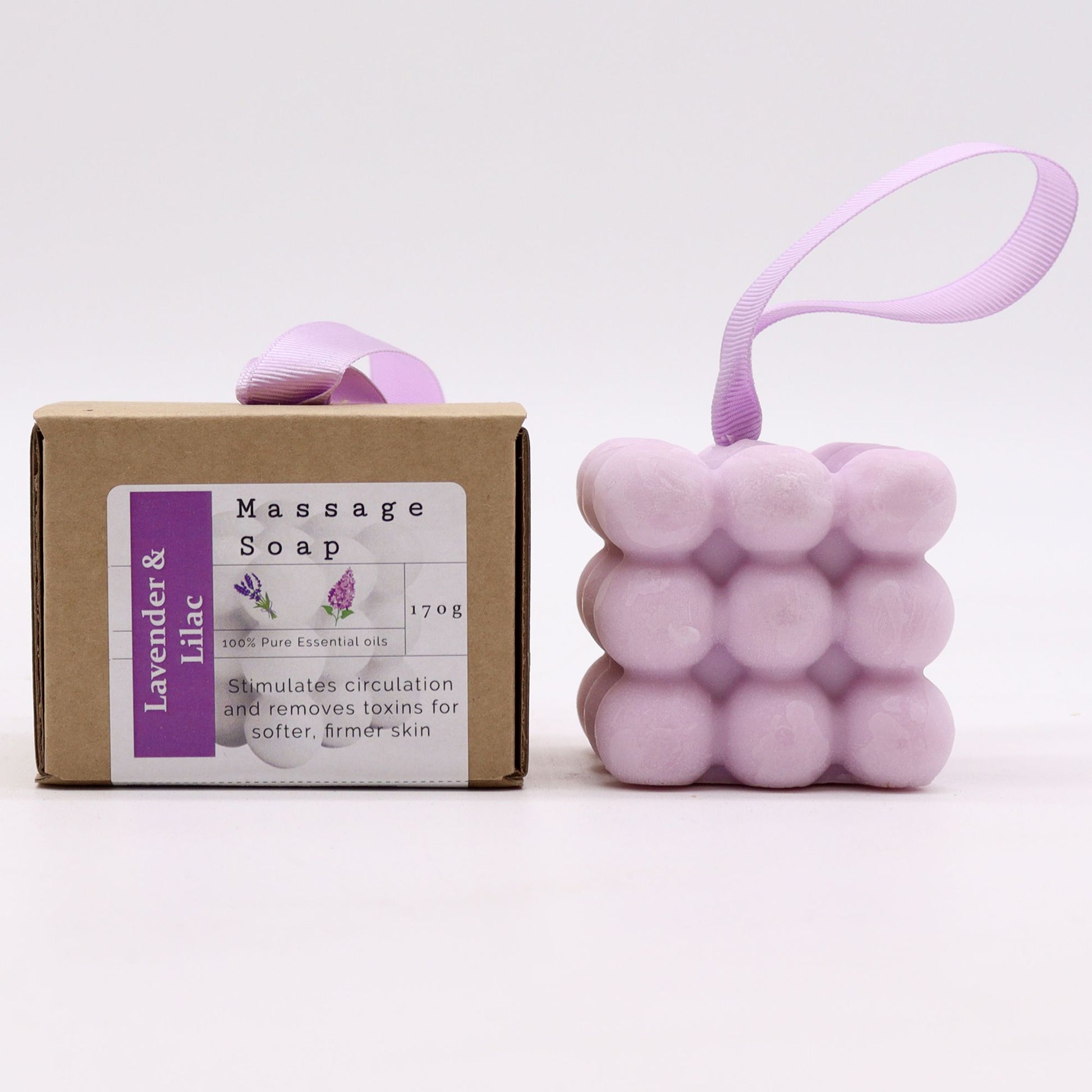 A purple massage soap bar with raised nubs for skin stimulation, scented with Lavender and Lilac, inside its individual box.