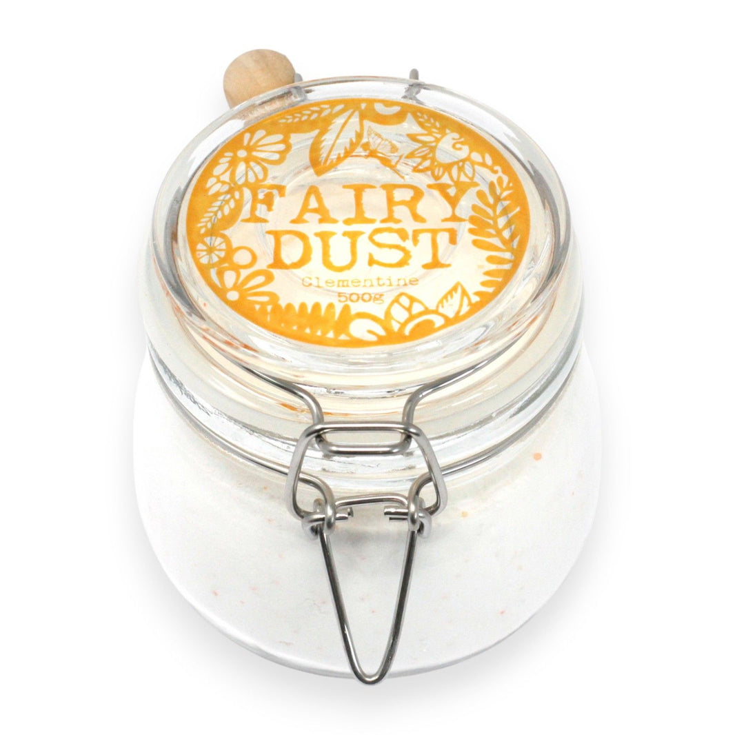 A large glass jar of 500g white and orange-flecked bath powder with a wooden scoop and a classic silver-clasp lid.