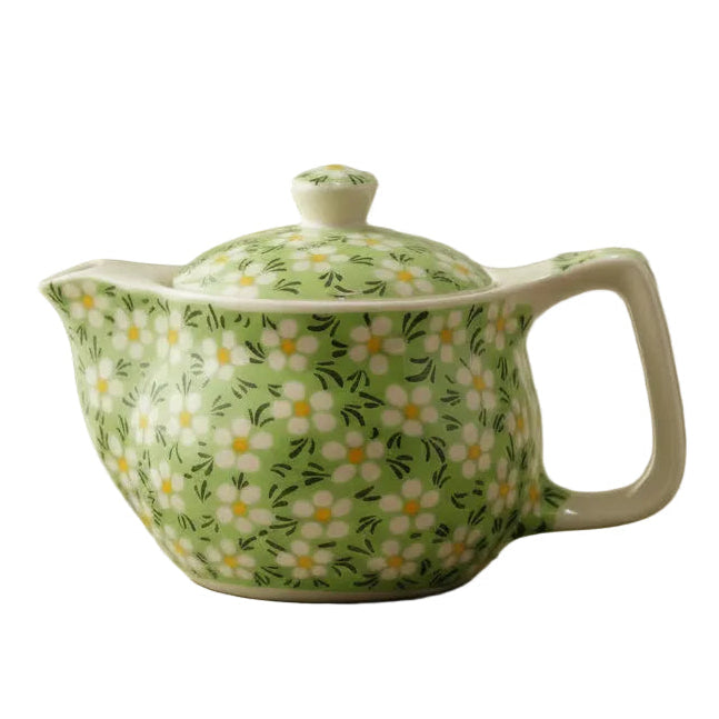 A small ceramic teapot with a light green background and white daisy flower patterns for brewing artisan herbal tea.