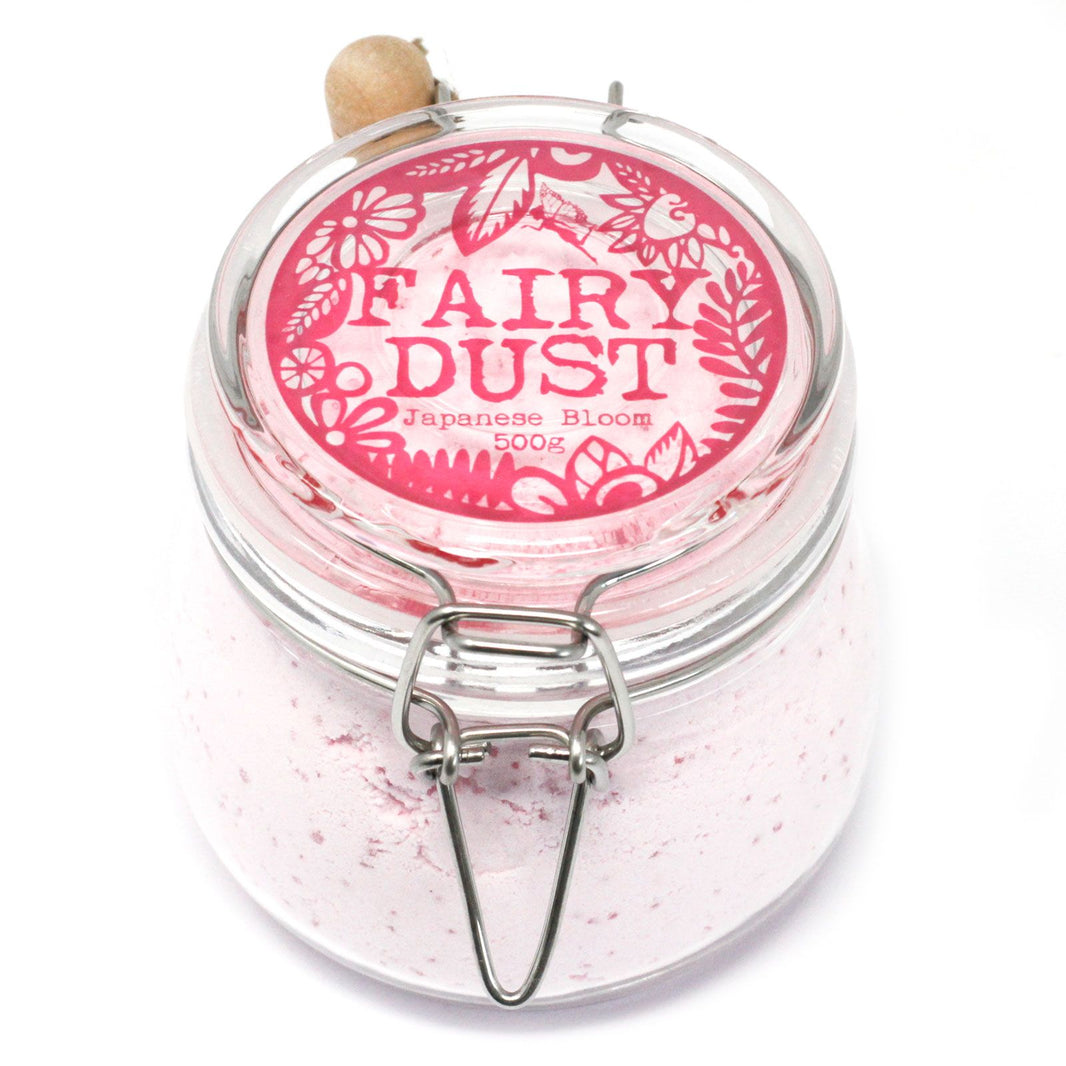 A high-end glass jar filled with 500g of soft pink aromatherapy bath powder and a small wooden measuring spoon.