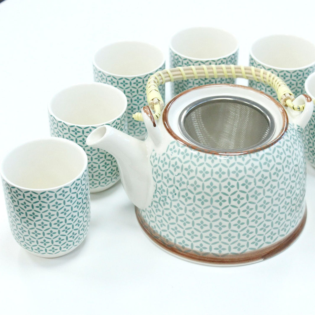 A light green ceramic teapot set with a matching warmer and cups, featuring a detailed, textured mosaic pattern.