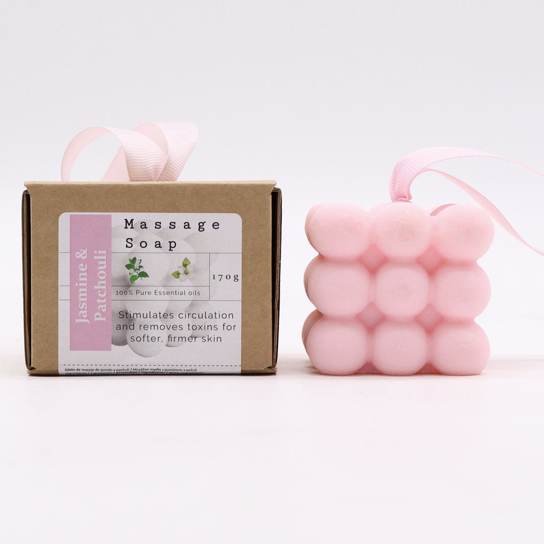 A pink massage soap bar with rounded nubs for muscle relief, scented with Jasmine and Patchouli, in its branded gift box.