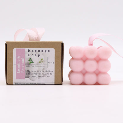 A pink massage soap bar with rounded nubs for muscle relief, scented with Jasmine and Patchouli, in its branded gift box.