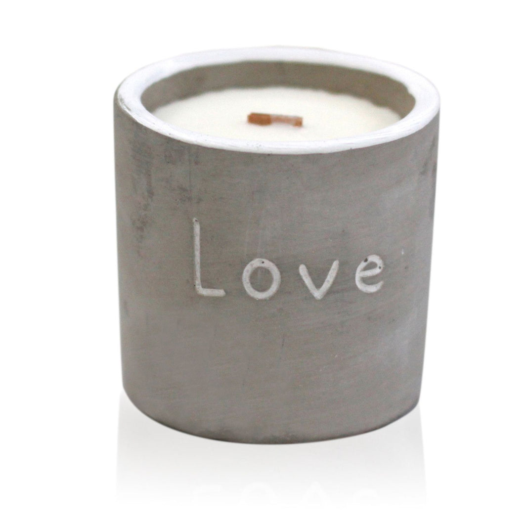 A medium-sized grey concrete candle pot with "Love" embossed on the front, containing a smooth, hand-poured soy wax candle.