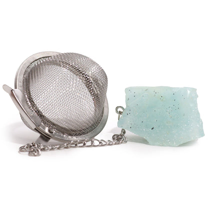 Silver tea infuser ball on a chain with a raw light blue aquamarine crystal charm for calming and peaceful tea rituals.
