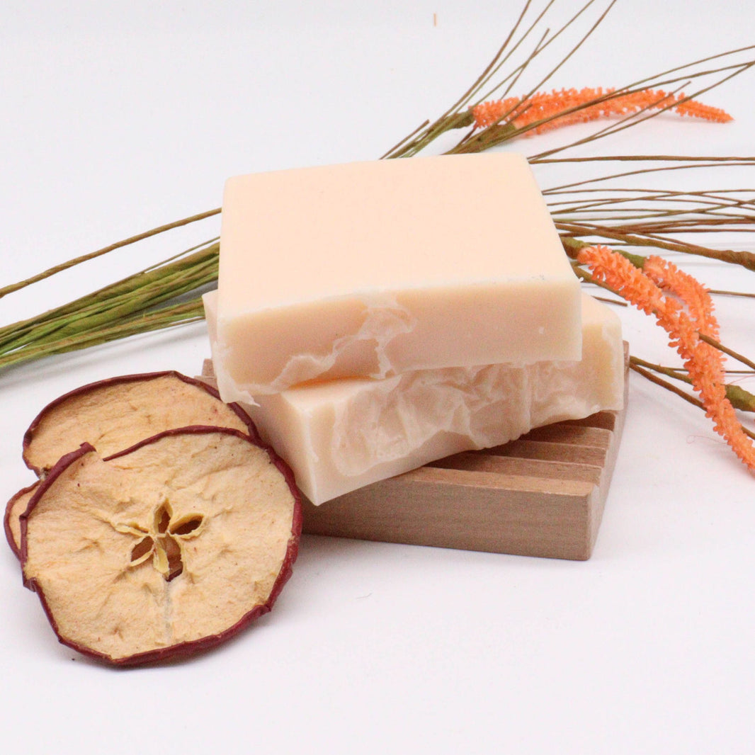 A 100g handcrafted artisan soap slice with peach and white layers, decorated with a dried flower accent.
