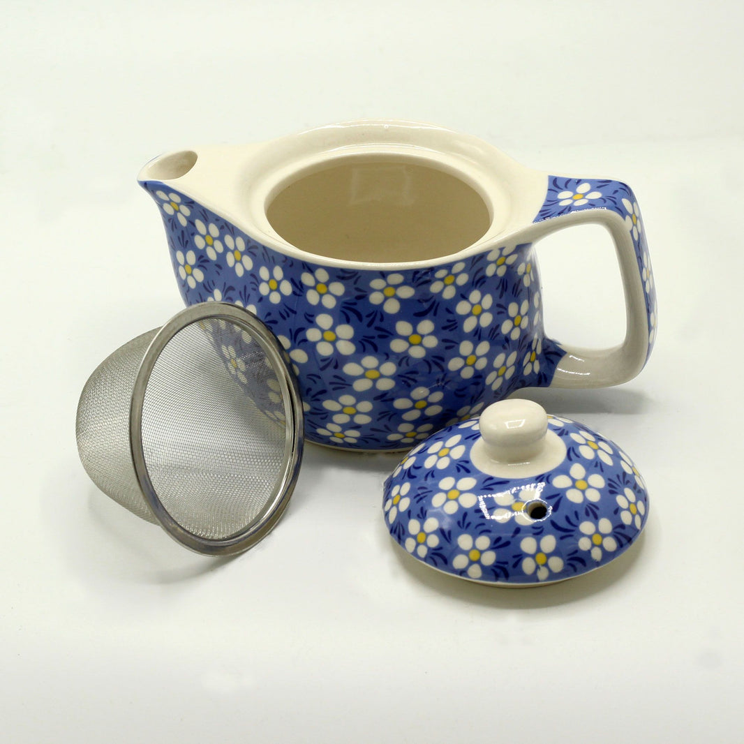 A small white ceramic teapot decorated with a blue background and white daisy flower patterns.