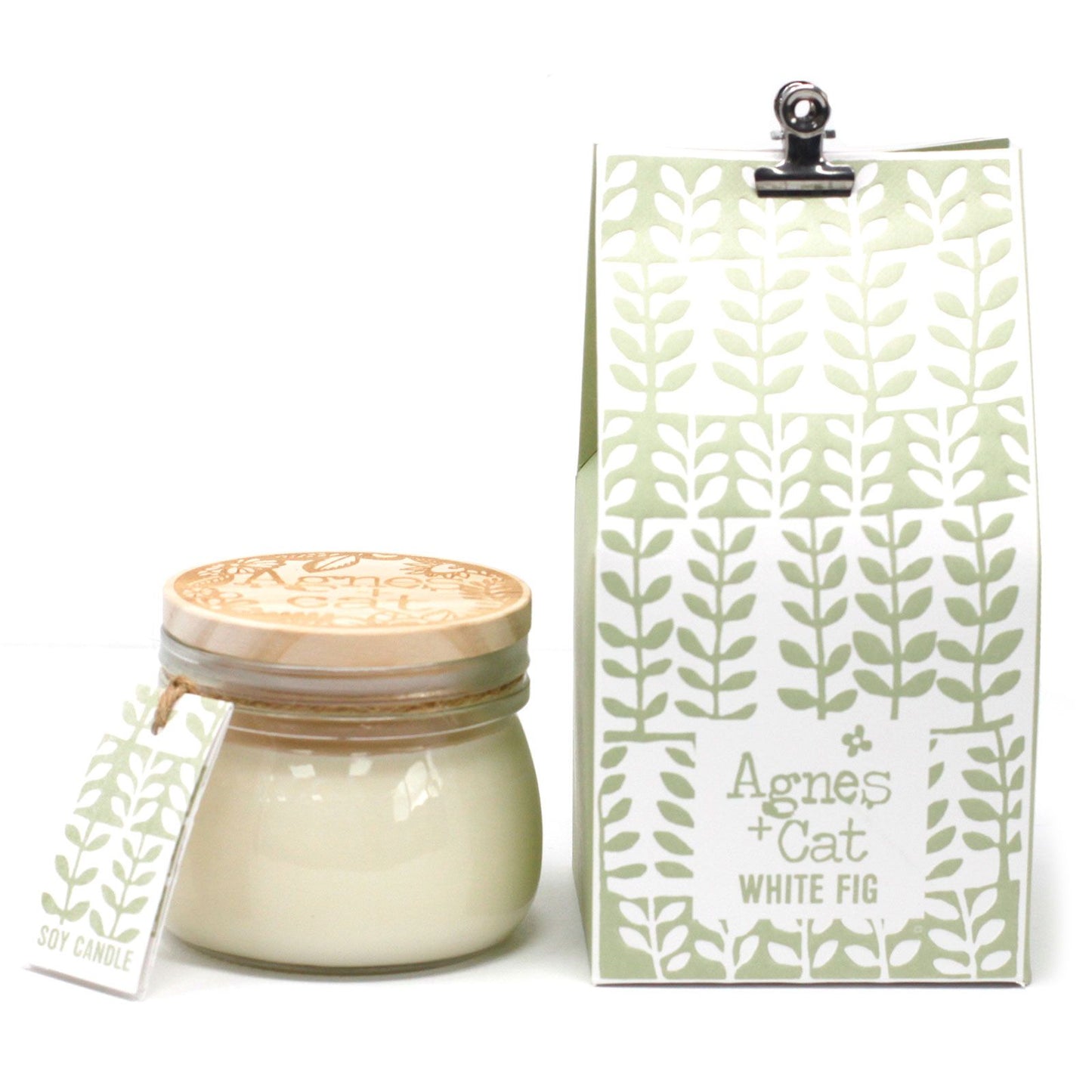 A small glass jar with a wire-bale lid containing a white fig-scented candle with an elegant green and white label.